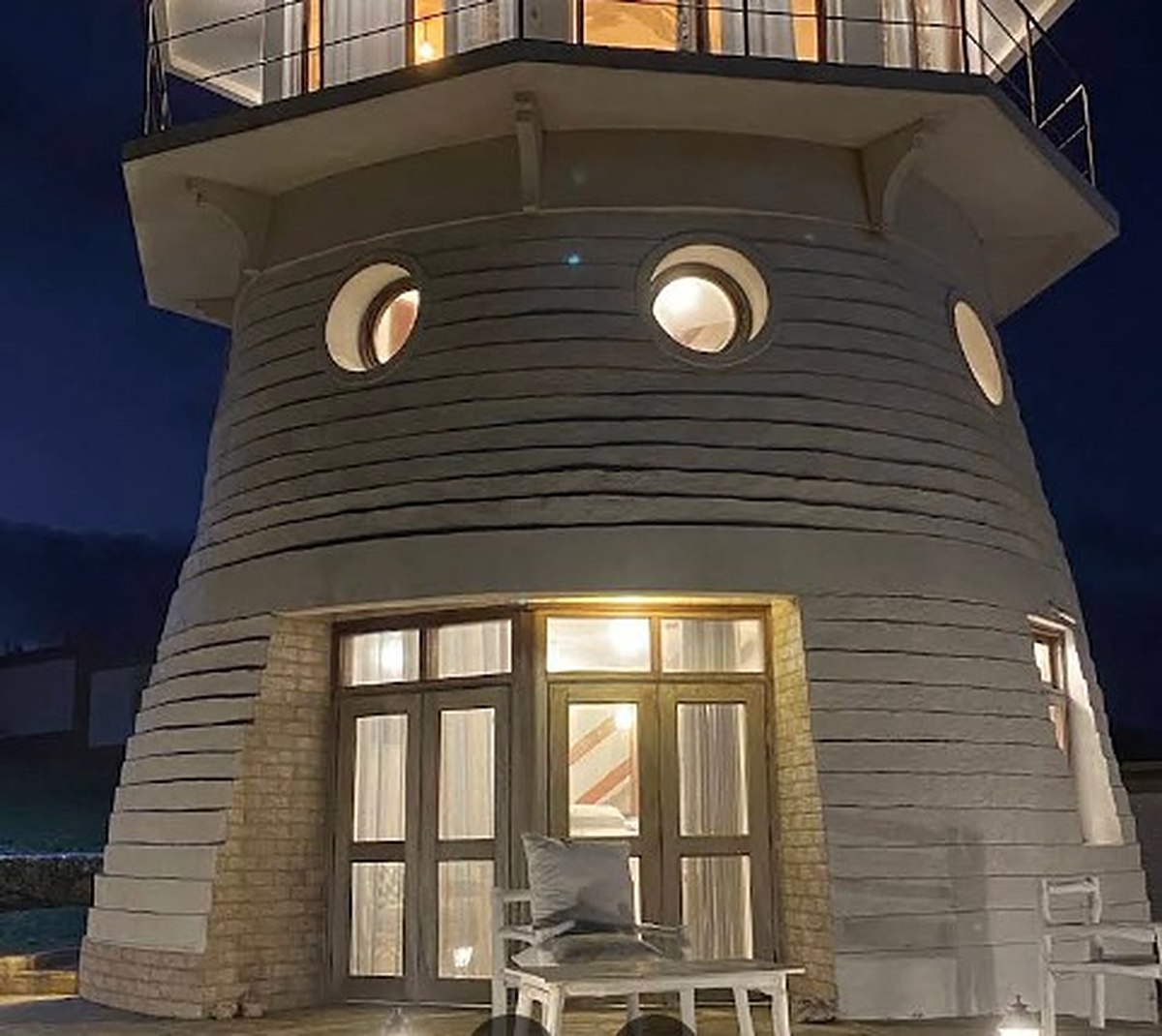 The lighthouse tower suite lit up at night, windows glowing